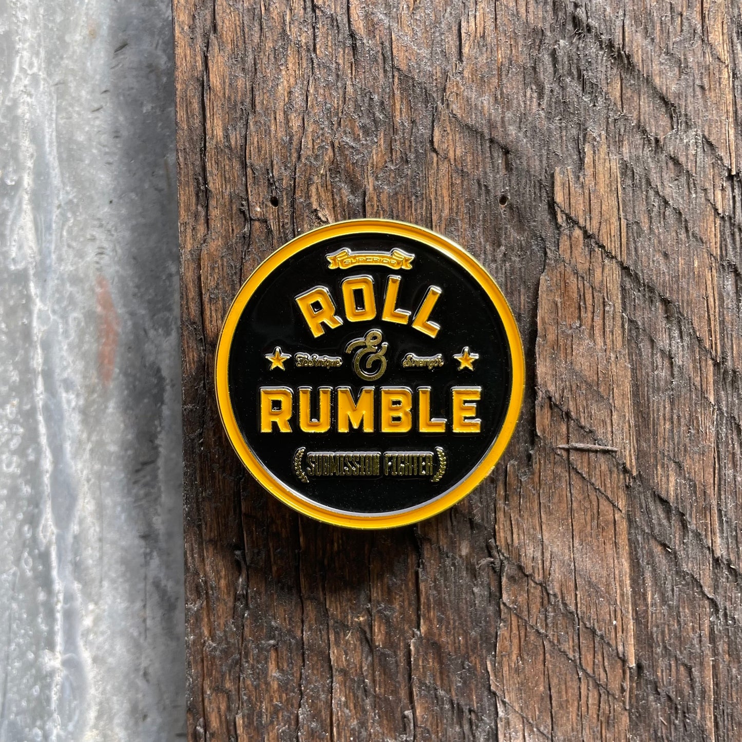 The iconic ROLL & RUMBLE round logo pin, gleaming in a vivid golden yellow hue that commands attention and showcases your passion for the sport in style.