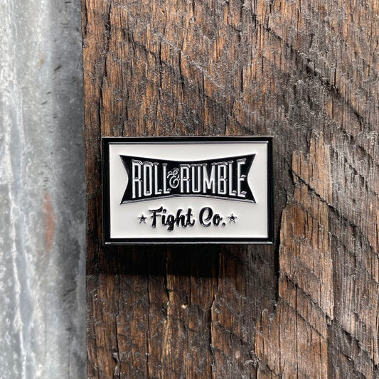 The classic ROLL & RUMBLE logo with its banner displayed in bold black and white, a timeless design that pays homage to the roots of Jiu-Jitsu.